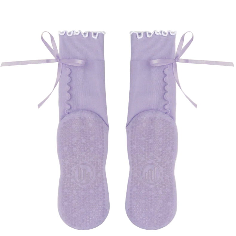 Pair of lavender socks with ruffled white top and ribbons on a beige background