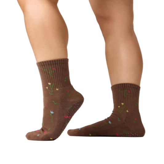 Brown socks with floral patterns worn by a person on a plain background